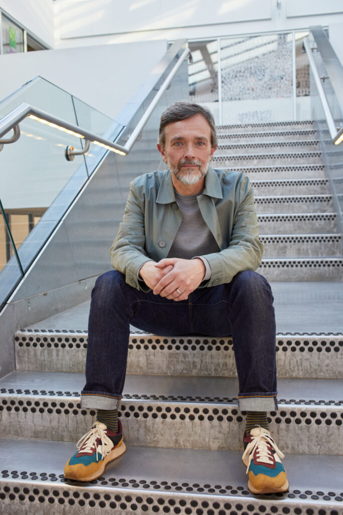 Senior lecturer Andrew Johnson sits on the metal stairs of the Guntons building at Norwich University of the Arts