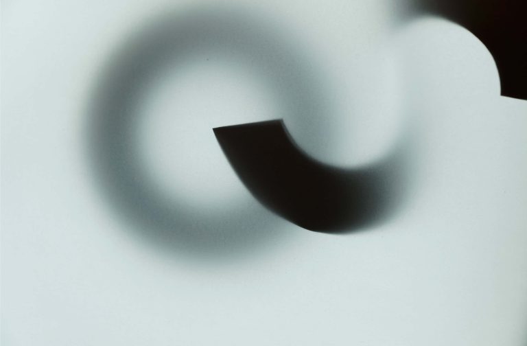 Shadows of black circular cut paper against a pale backdrop.