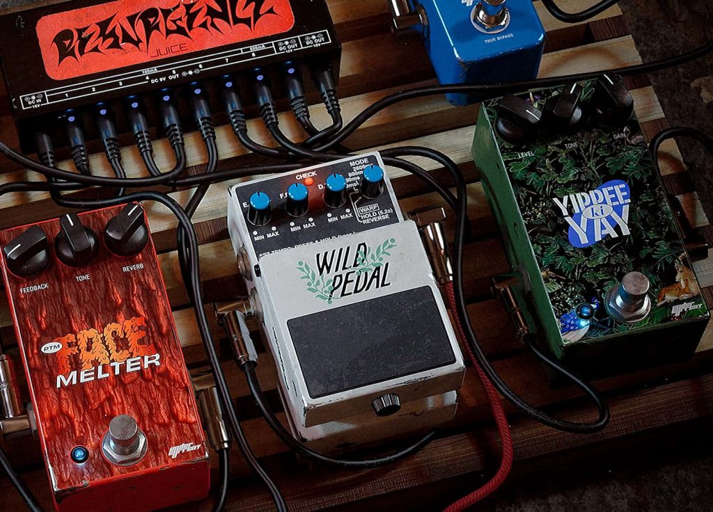 Computer generated image created by George Kee. A top down view of a pedal board. Three pedals can be seen all connected by black wires, one red, one grey and one dark green.