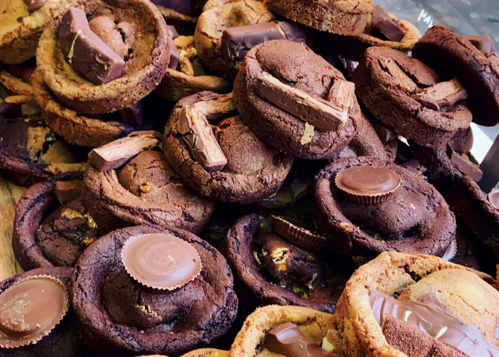 Full frame photo of thick chocolate cookies, with bits of chocolate bar stuck on top.