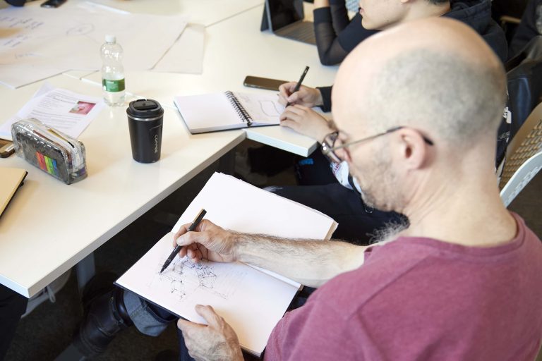 Male Interior Design student sketching in a book.