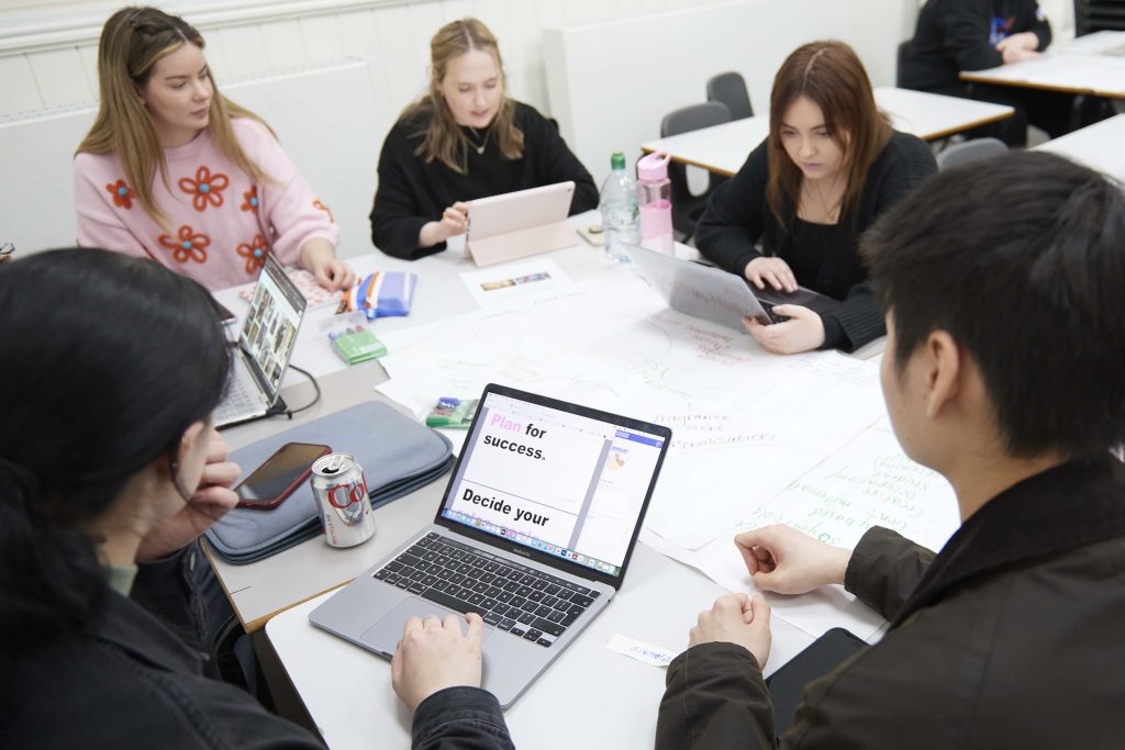 A group of Interior Design and Fashion Marketing and Business students working around a table with their laptops.