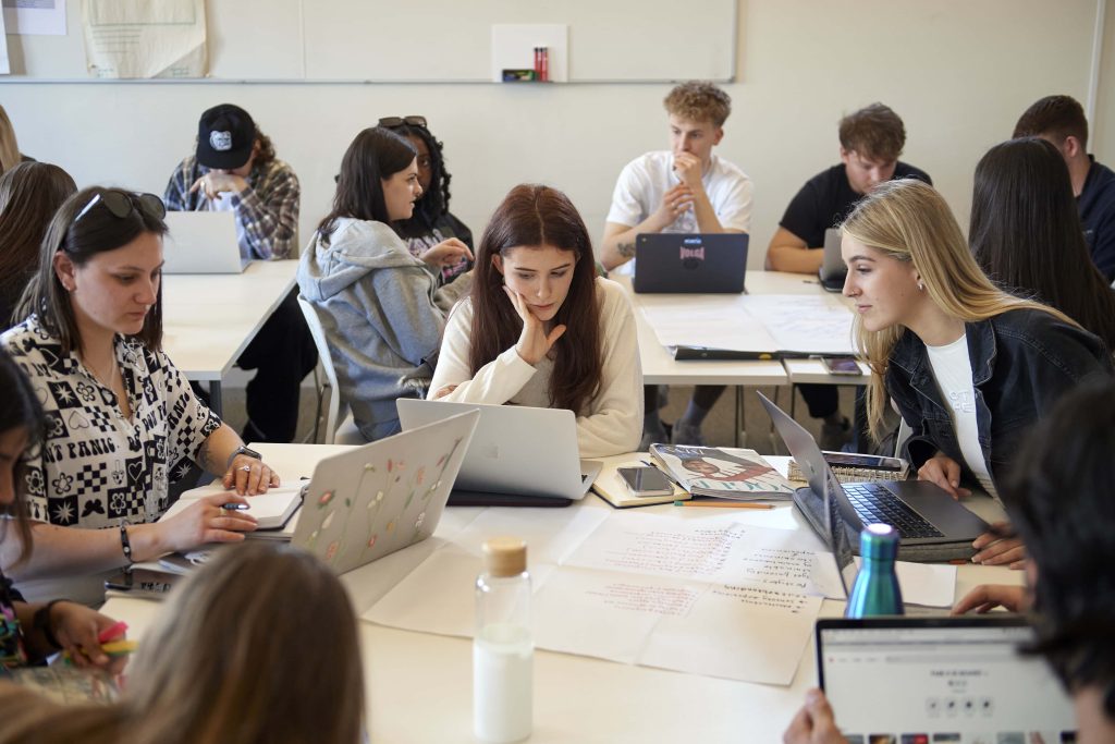 Groups of Interior Design and Fashion Marketing and Business students sitting around tables with their laptops.