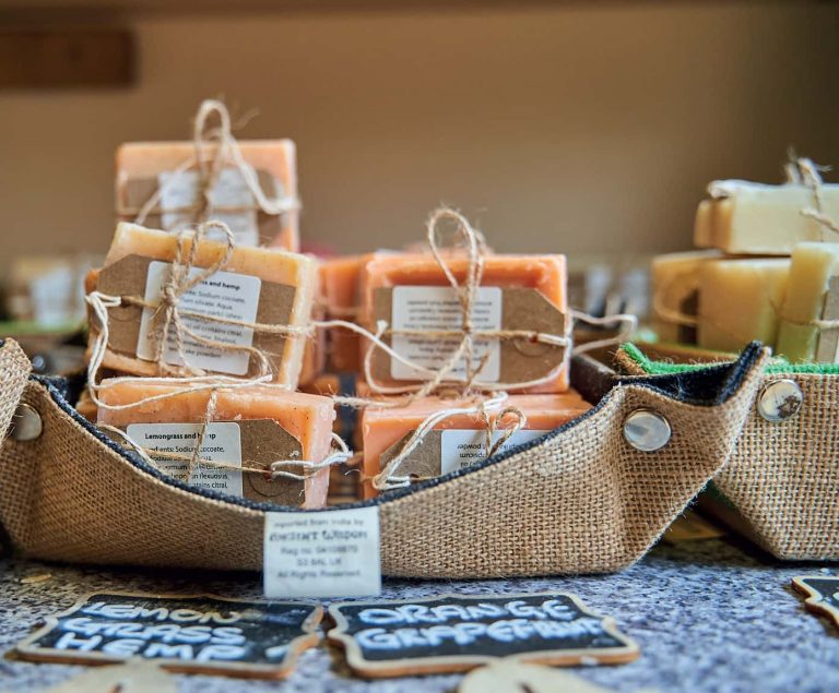 A stack of orange soaps wrapped in twine sits in a brown basket.