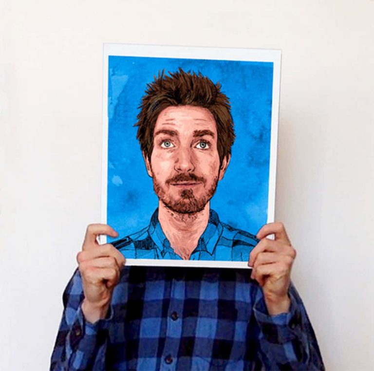 A photo of Matthew Brazier holding an illustration up of himself covering his face.