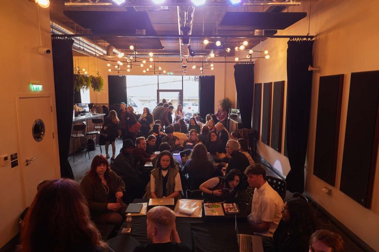 Wide shot of a large room with several groups gathered round tables