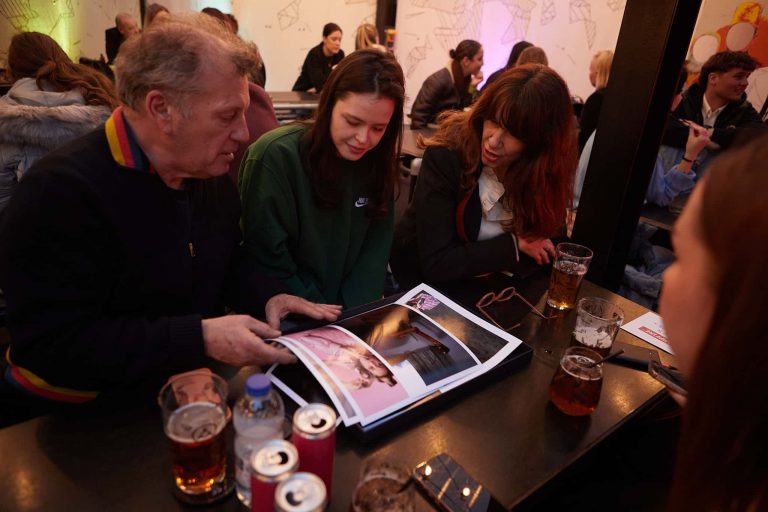 Four people are seated around a table, examining a collection of photos