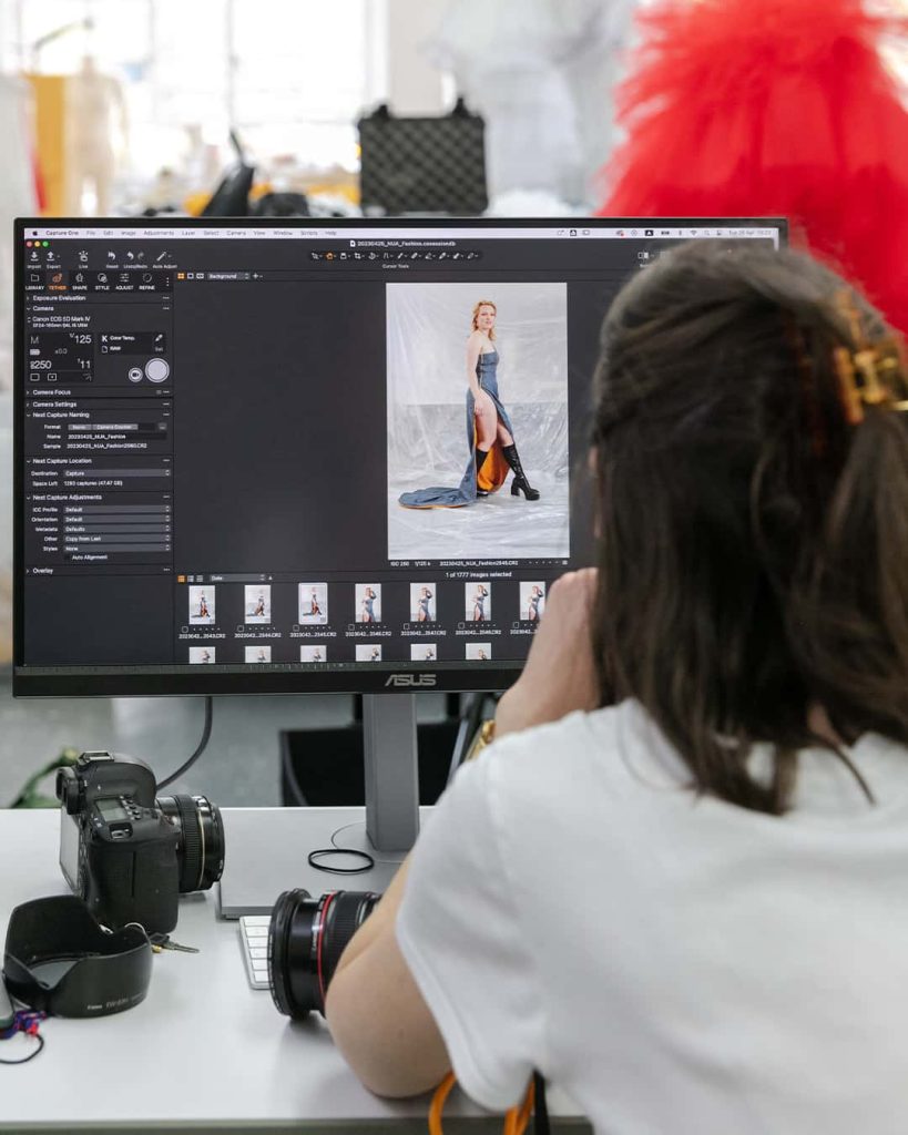 A photo of Denisa working at a computer screen editing images