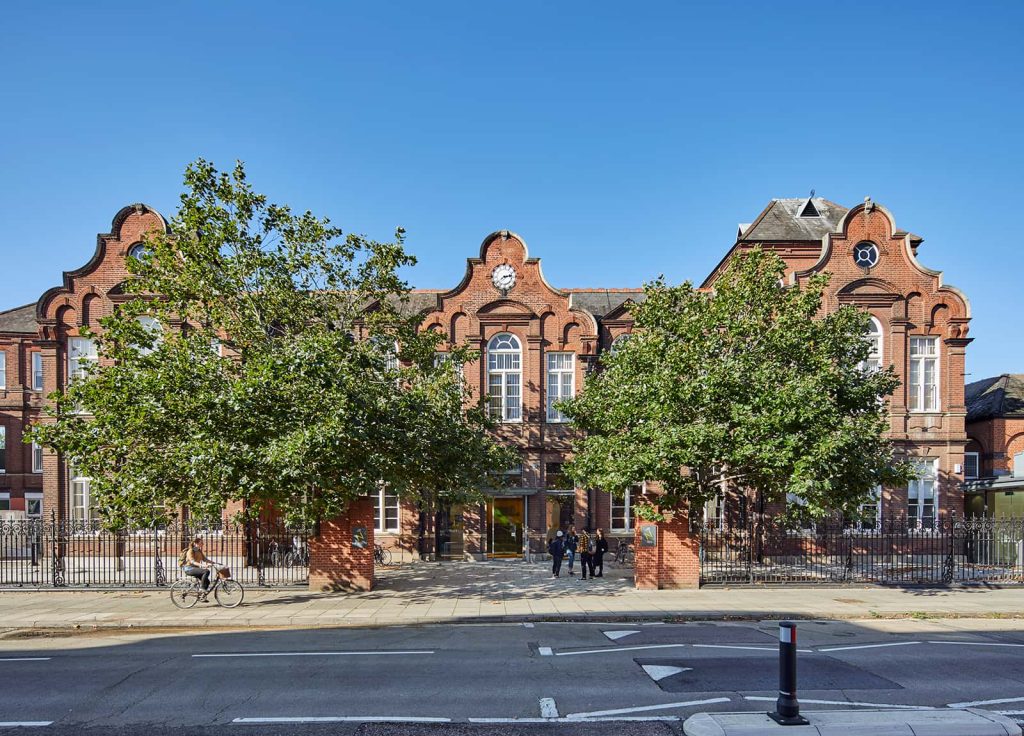 Duke Street building. Photograph of a red brick building with large windows with rounded tops. Two large, leafy trees stand either side of the entrance.