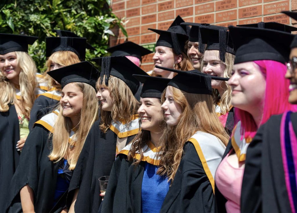 A photo of Norwich University of the Arts graduates smiling for a photo at Graduation 2023.