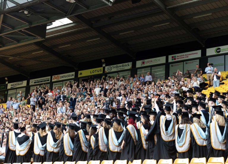 A photo of Norwich University of the Arts graduates with their friends and family, celebrating and clapping at Graduation 2023.