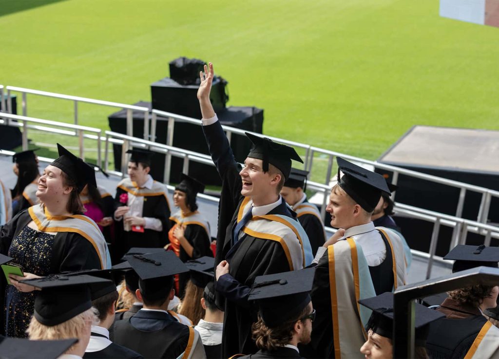 A photo of Norwich University of the Arts graduates waving at Graduation 2023.