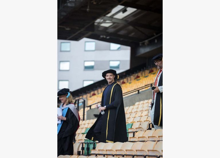 A photo of Russel Tovey walking down stadium stairs in Norwich University of the Arts graduation 2023.