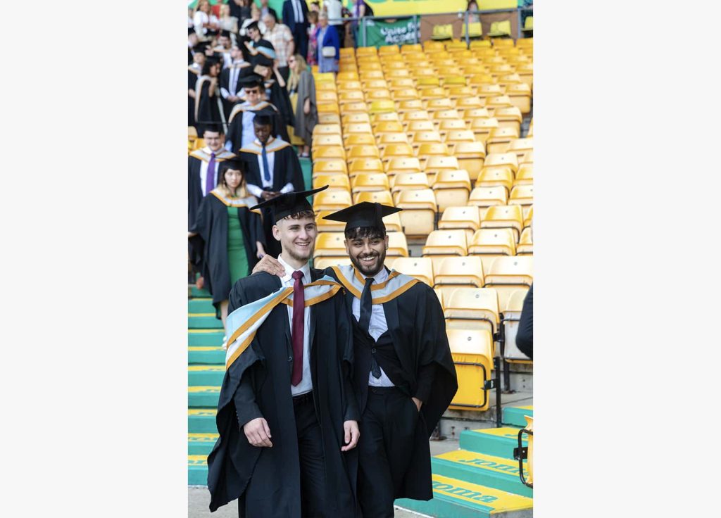 A photo of two graduates smiling and walking together at Graduation 2023.