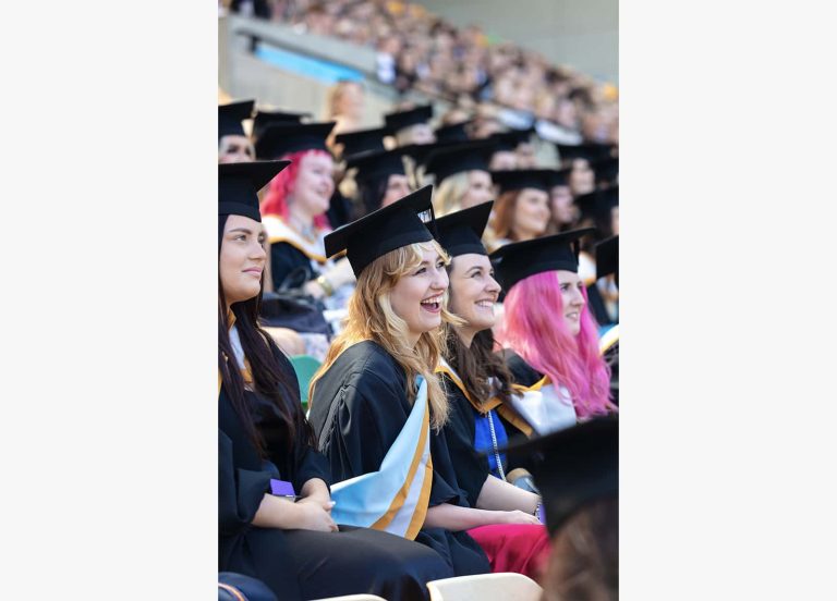 A photo of Norwich University of the Arts graduates laughing at Graduation 2023.