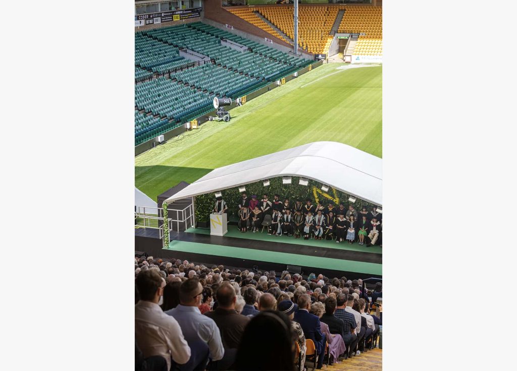 A photo of a stage with a large number of people sat down in-front of it at Graduation 2023.