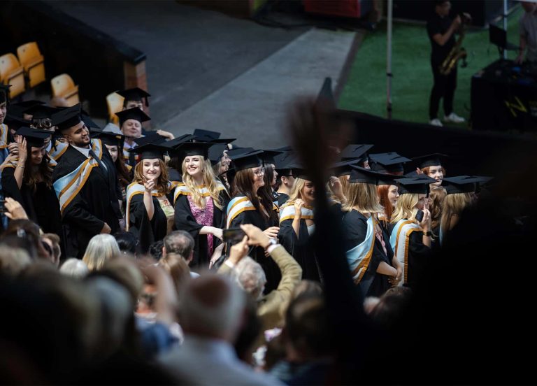 A photo of Norwich University of the Arts graduates waving to their friends and family at Graduation 2023.