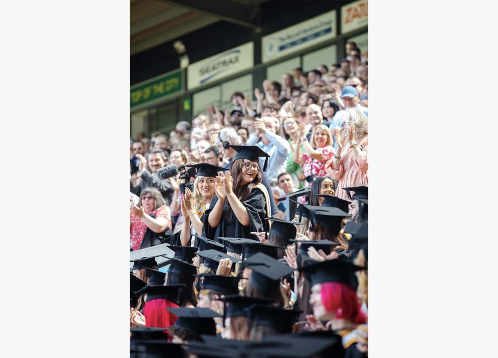 A photo of Norwich University of the Arts graduates smiling and clapping their hands at Graduation 2023.