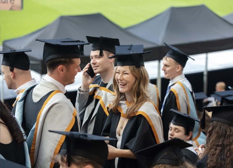 A photo of Norwich University of the Arts graduates laughing at Graduation 2023.