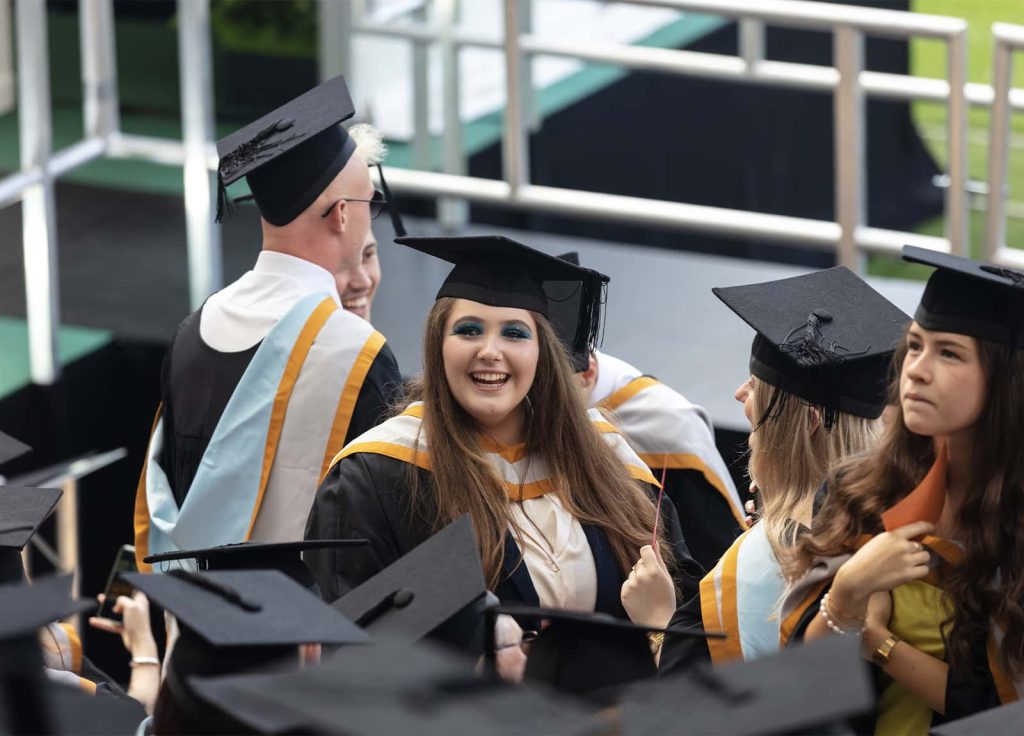 A photo of a female student smiling and laughing at Graduation 2023.