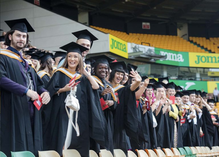 A photo of Norwich University of the Arts graduates smiling and waving at Graduation 2023.