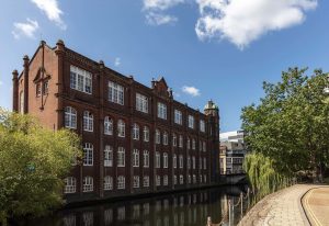 A photo of St. Georges building and the River Wensum on a summers day.