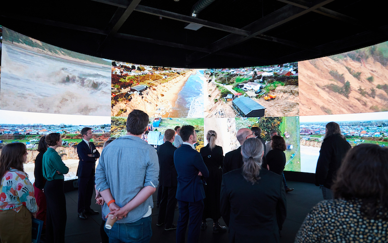 An audience viewing images of Norfolk coastal erosion on a 360 LED screen.