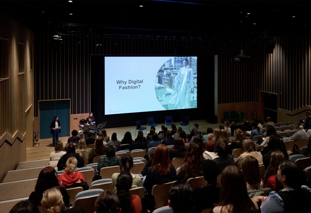 A photo of the Digital Fashion Symposium at Duke Street Riverside lecture theatre. The image is of a large audience sat down and listening to a talk.