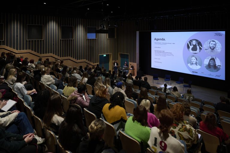 A photo from the Digital Fashion Symposium at Duke Street Riverside. The photo is of the lecture theatre full of people listening to Emma Thompson introducing the event.