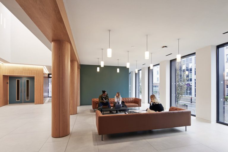 View of foyer space with two large sofas facing each other and students working.