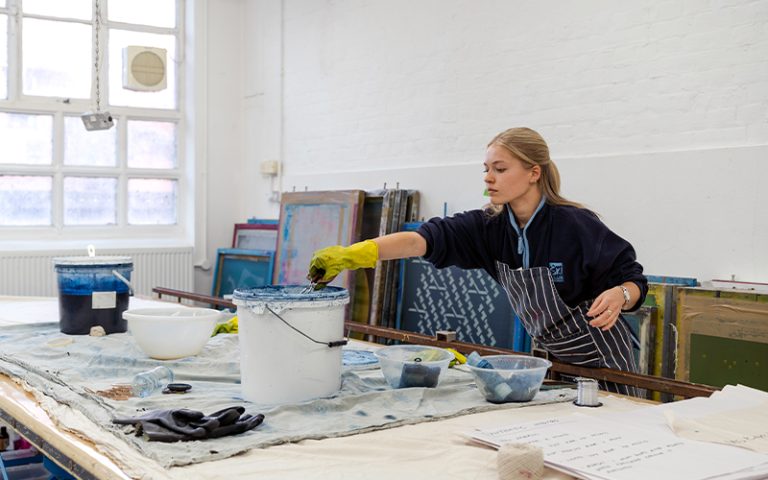 A photo of a student dyeing fabric in an Indigo workshop.