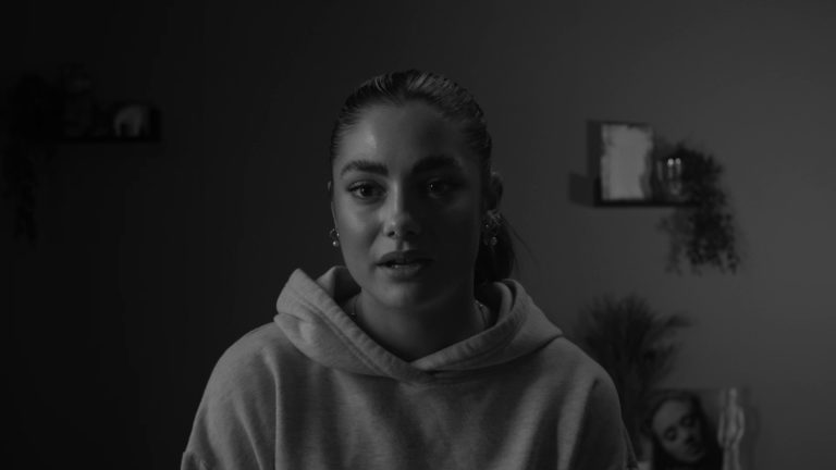 Still from student film 'Love, Me'. Head and shoulders shot of interviewee wearing a light coloured hoody; the image is black and white.