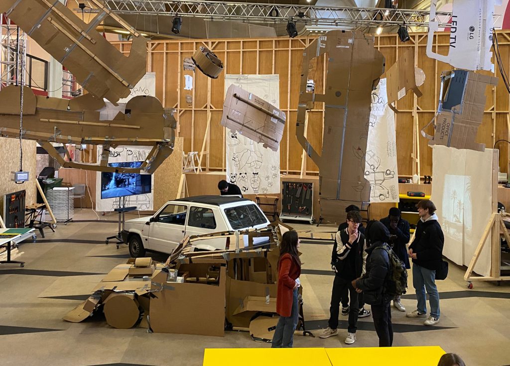 The project studio at Norwich University of the Arts where a Fiat Panda is surrounded by 1:1 scale cardboard cutout replicas hanging from the ceiling around it