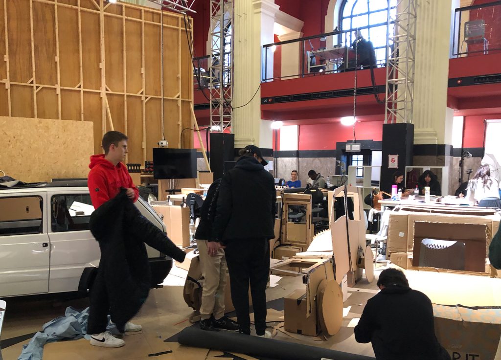 The project studio at Norwich University of the Arts where a Fiat Panda is surrounded by 1:1 scale cardboard cutout replicas hanging from the ceiling around it