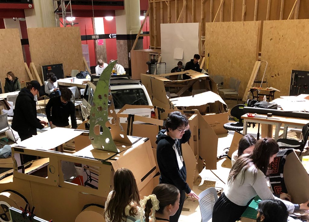 The project studio at Norwich University of the Arts where a Fiat Panda is surrounded by 1:1 scale cardboard cutout replicas hanging from the ceiling around it