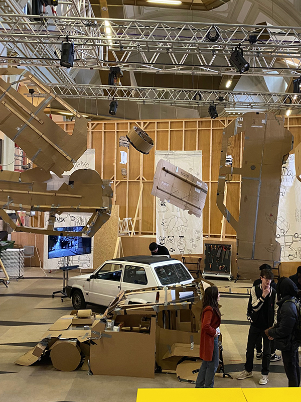 The project studio at Norwich University of the Arts where a Fiat Panda is surrounded by 1:1 scale cardboard cutout replicas hanging from the ceiling around it