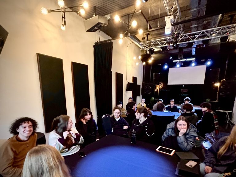 A small group of people are gathered around a circular blue table.