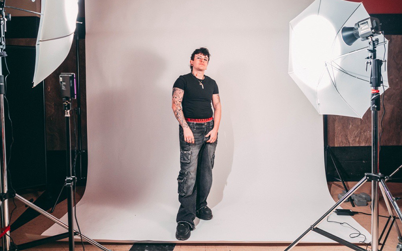 Adrian Sweeney Golano standing on a white backdrop, on a photoshoot set in Bank Plain with lights either side of him.