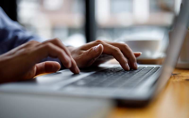 A photo of a person working at a laptop, cropped in to their hands