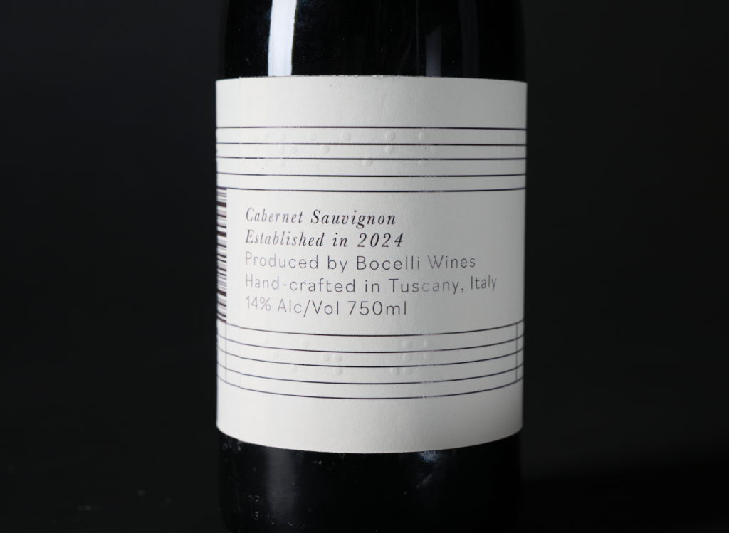 The image shows a wine bottle label with text detailing a 2024 Cabernet Sauvignon by Bocelli Wines. It is hand-crafted in Tuscany, Italy, with 14% alcohol content and a volume of 750ml.