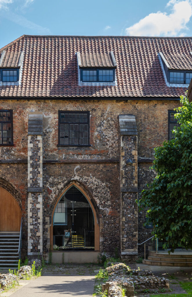 A landscape photograph of Norwich University of the Arts' East Garth building, in Norwich. The photo is taken from underneath a cobbled archway looking towards the building.