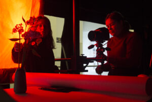 People working in a dark studio taking photographs of a potted flower