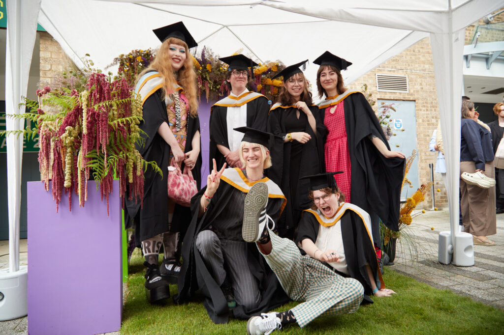 Group outside graduation venue, they are having a picture taken and are smiling