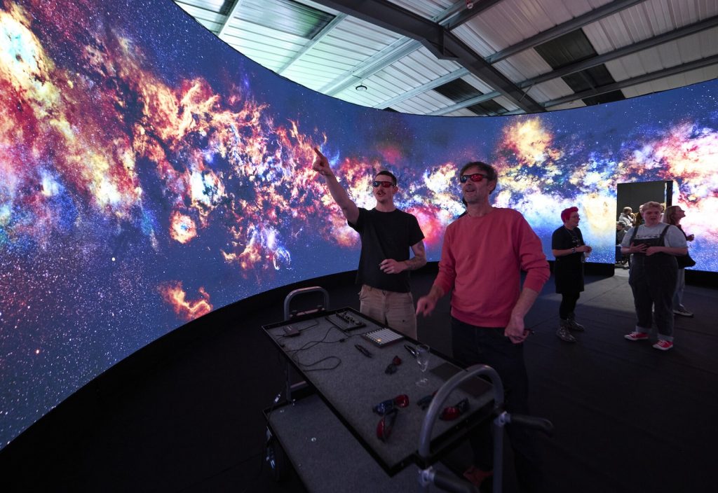 Researchers in the Immersive Visualisation and Simulation Lab explore images of space on the 360 screen wearing 3D glasses.