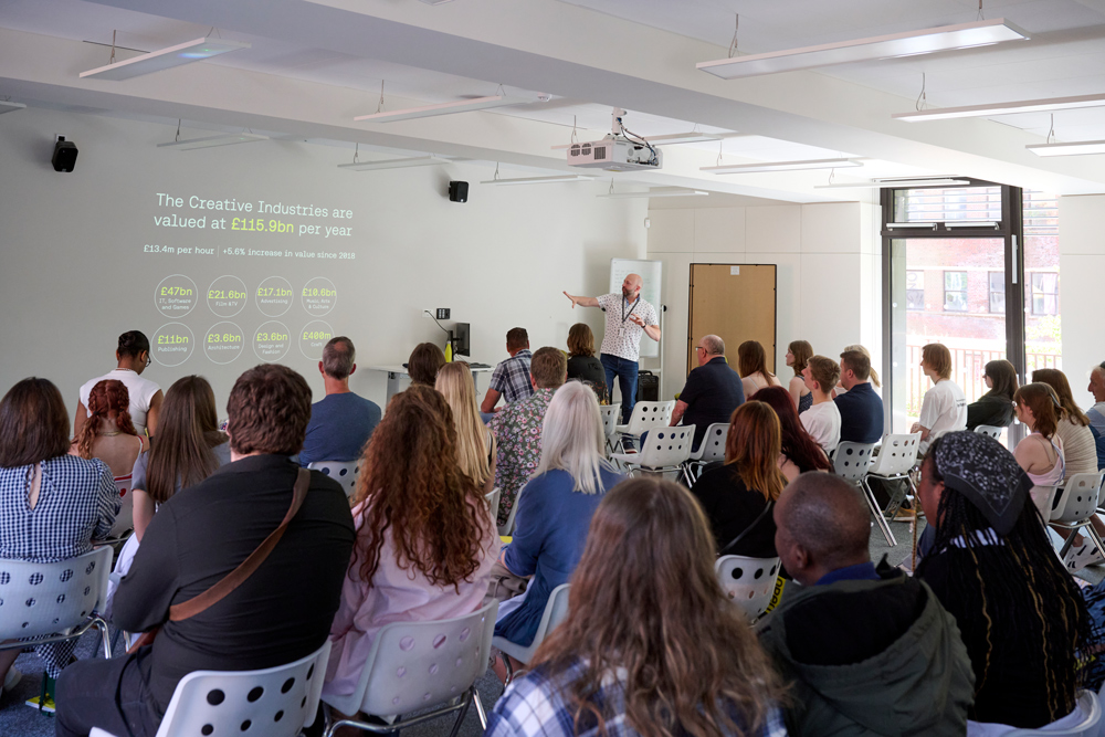 A photograph of a seminar room at Norwich University of the Arts, where an academic is giving a welcome presentation to visitors at an Open Day.