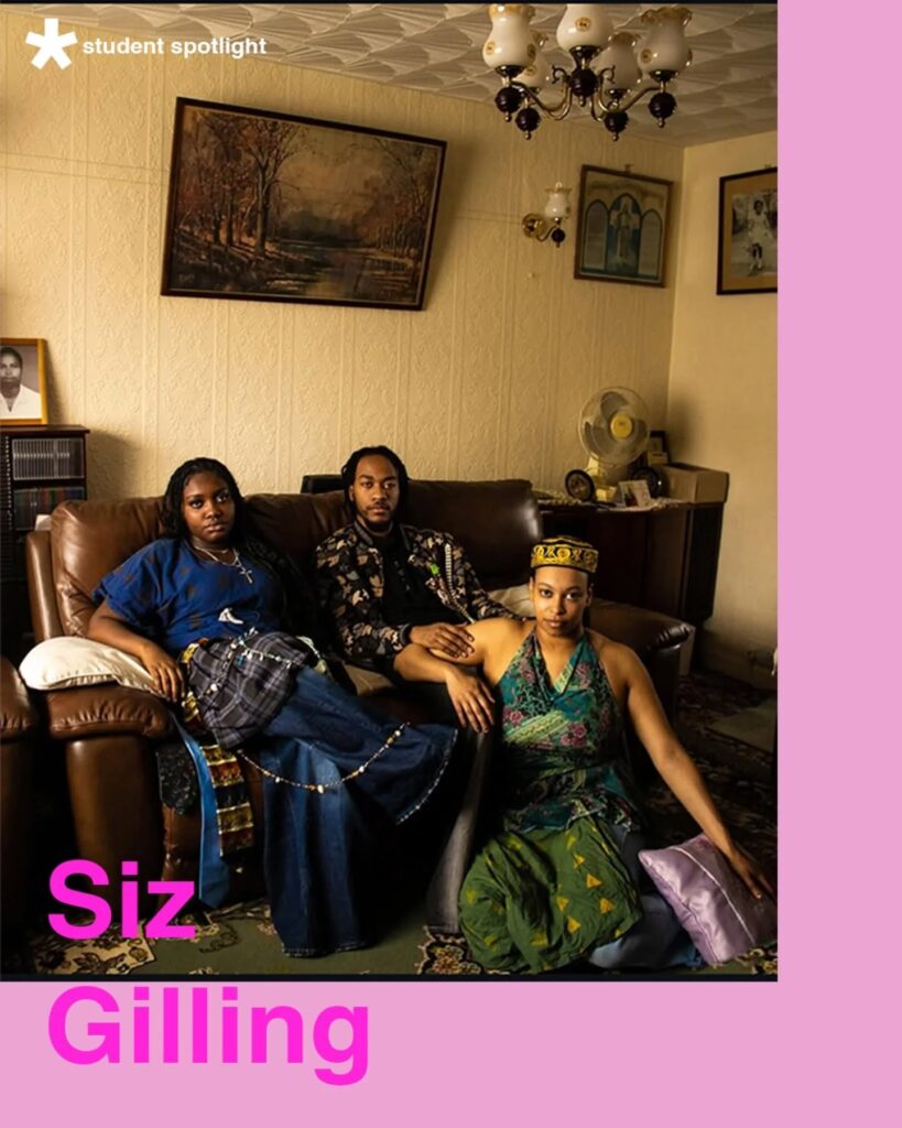 Three people sit together in a vintage-style living room with patterned wallpaper and framed art. Two sit on a brown sofa, and one sits on the floor. Text reads "student spotlight" and "Siz Gilling" in pink letters.