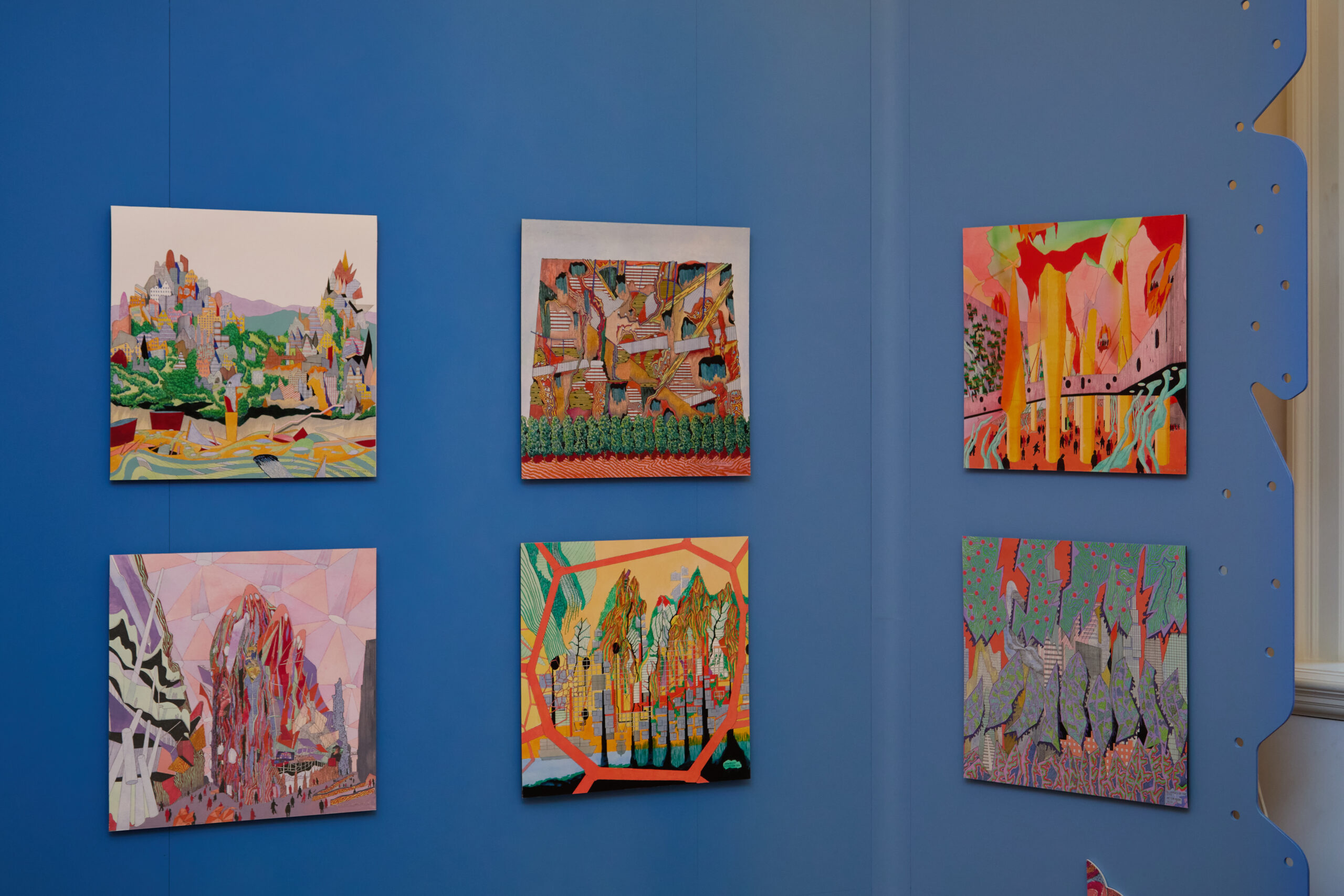 Six colourful abstract paintings are displayed on a blue wall, arranged in two rows of three. The artworks feature bright colours, geometric shapes, and imaginative landscapes.
