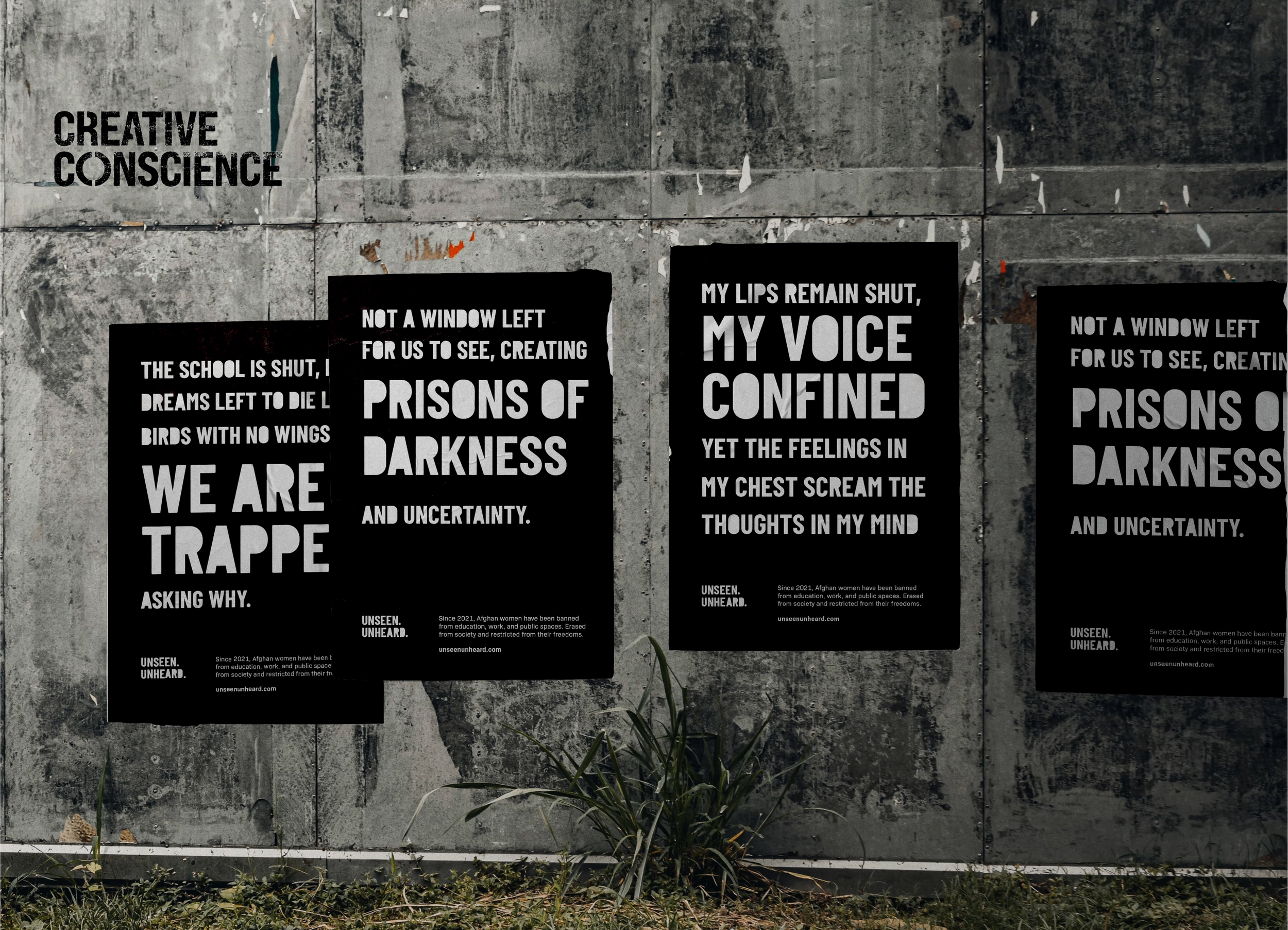 Four black posters with white text about confinement and uncertainty are pasted on a weathered concrete wall with the words "CREATIVE CONSCIENCE" above them. Grass grows along the base of the wall.