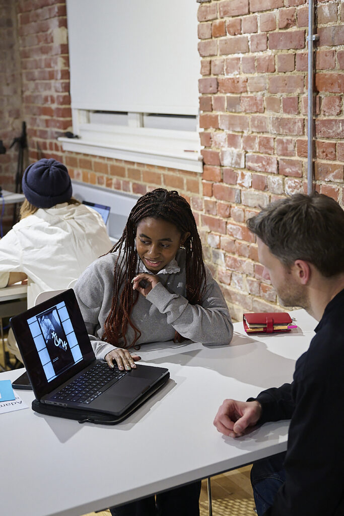 A man and woman sitting at a table looking at a laptop.