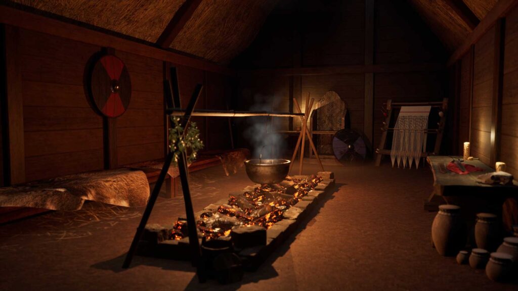 A dimly lit interior with a central fire pit, a large pot hanging over the flames, wooden benches, shields, woven items, and pottery along the walls.